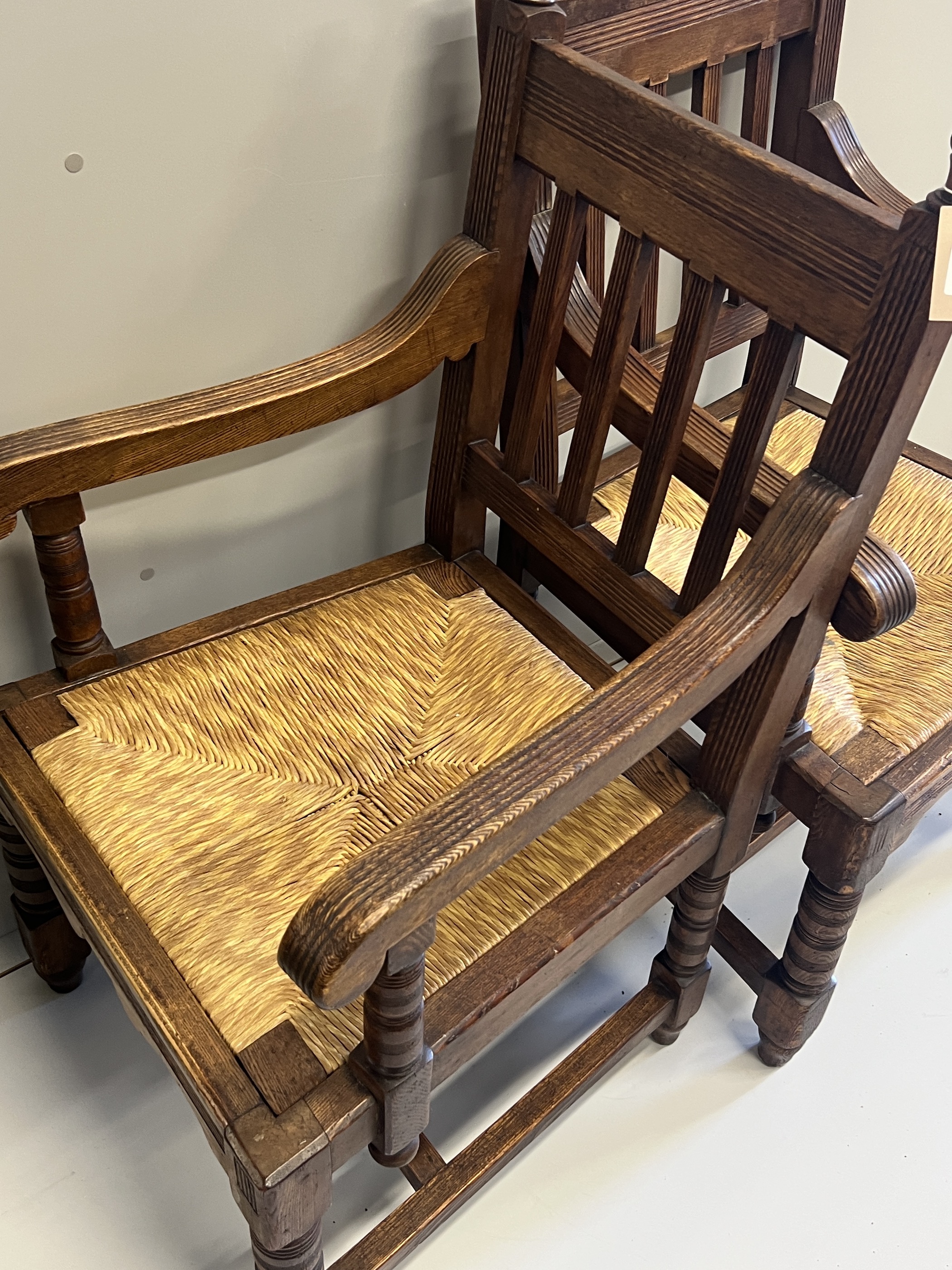 A pair of Victorian Arts & Crafts oak rush seat elbow chairs, width 58cm, depth 54cm, height 104cm